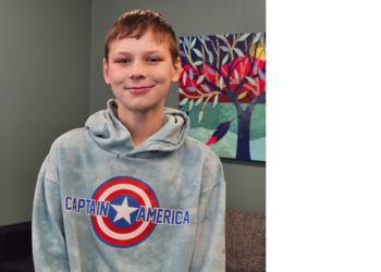 Daniel, 12, is wearing a Captain America sweatshirt and smiling at the camera.