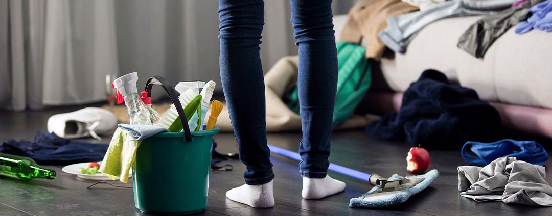 Picture of someone's legs standing in a room with their cleaning supplies, ready to start cleaning.