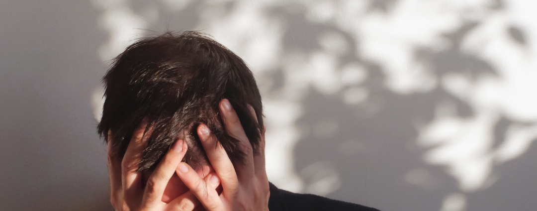 A white male holding his head in his hands