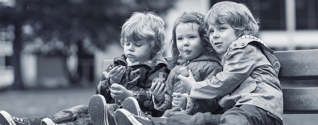 Ali, Betsy, and Dane on a park bench as toddlers