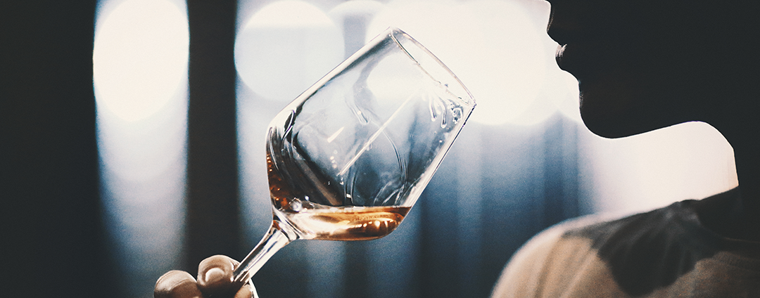 Picture of a woman holding a wine glass contemplating taking a drink of wine.