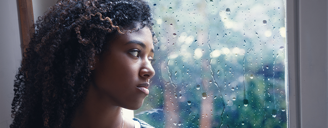 A women staring out the window watching the rain