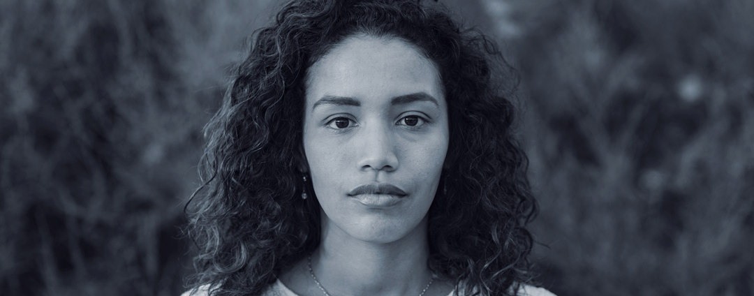 Hispanic woman looking at camera, somber expression on face