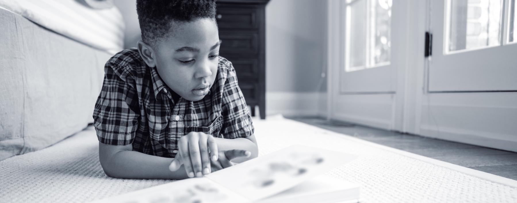 photo of a young boy reading a book on the floor