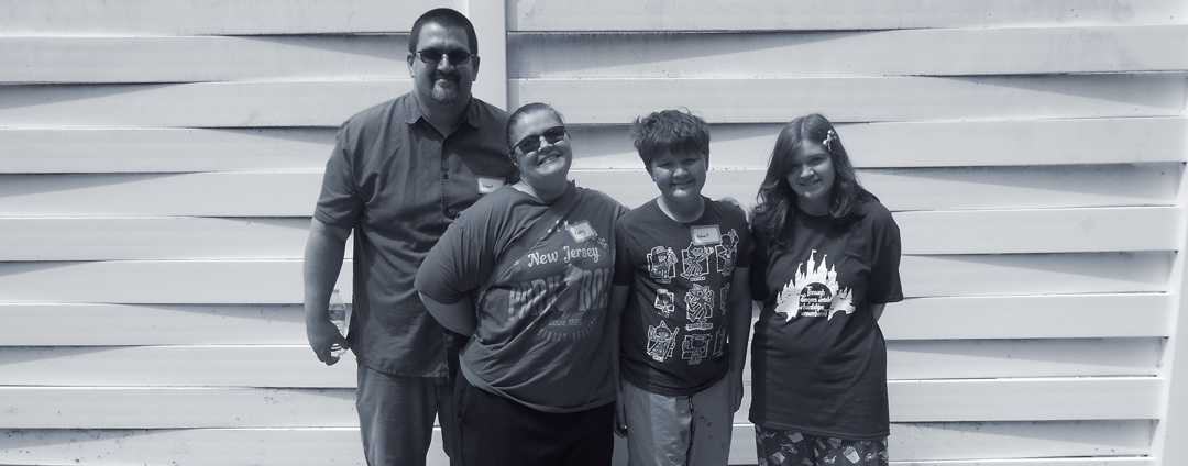 Kayleigh's family photo - a photo featuring dad, mom and brother alongside Kayleigh standing in front of a white fence.