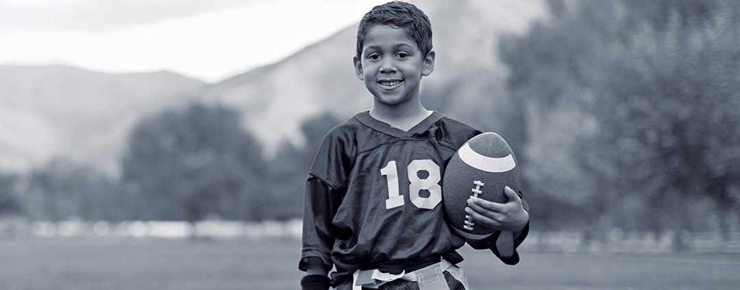 Photo of a young boy at football practice holding a football