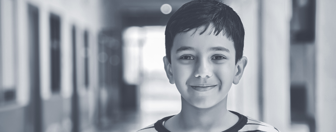 black and white photo of a young boy in an elementary school hallway
