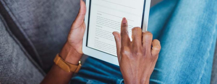 Picture of a Black person's hands scrolling a tablet to read an article