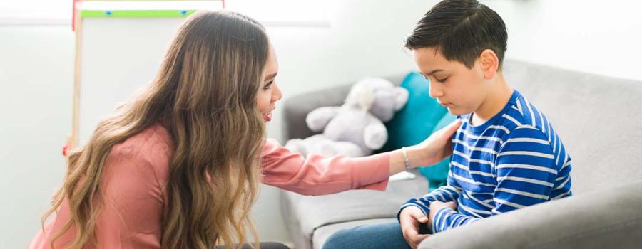 Picture of a woman comforting a child who is sitting on a couch.