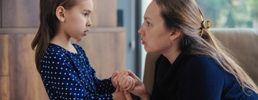 Mom holding a little girl's hand while the girl looks worried.