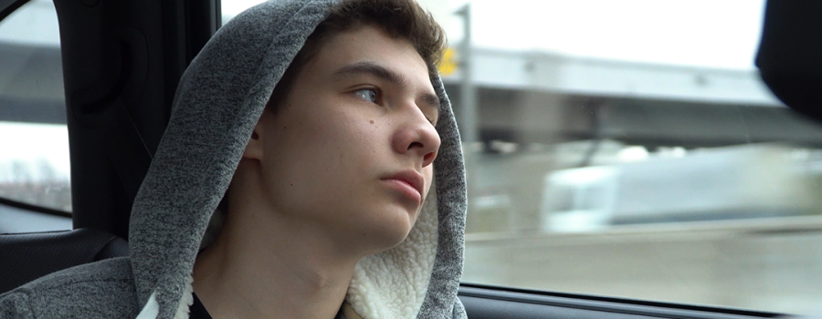 Teenage boy looking out car window