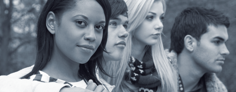A diverse group of four teenagers with their arms wrapped across their backs/shoulders