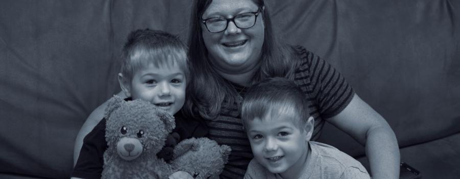 Elyssa and her twin boys sitting on a couch smiling at the camera