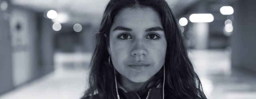 Teenage girl wearing headphones, looking at the camera with a pensive look