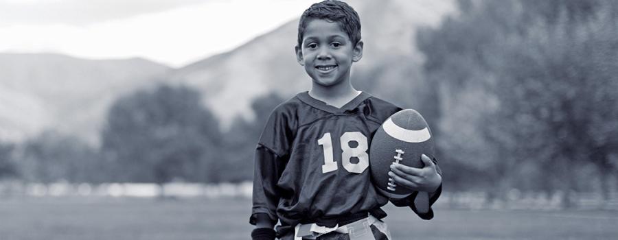 Photo of a young boy at football practice holding a football