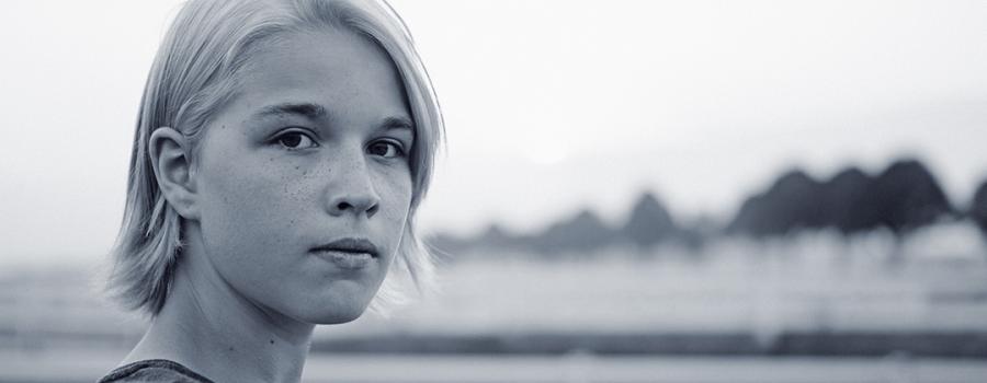 Photo of a teenage girl on in a rural setting looking at the camera