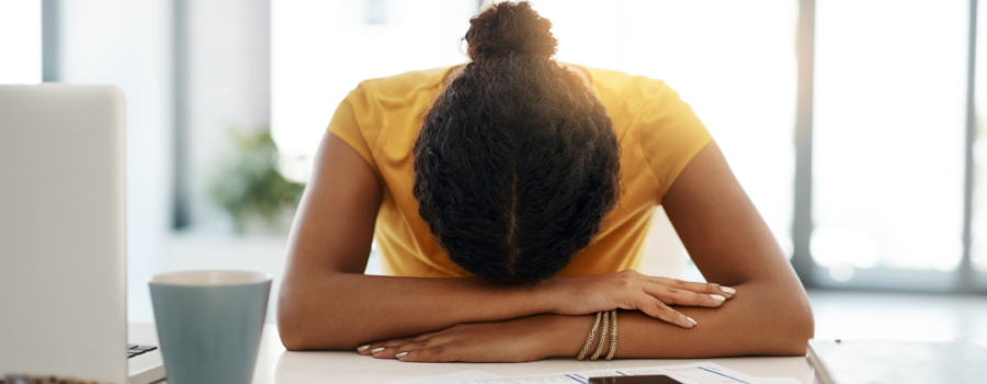 A stressed woman laying her head on her desk.