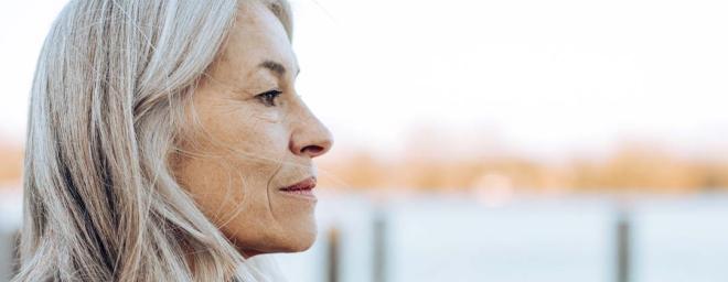 Older woman looking out onto a lake pensively