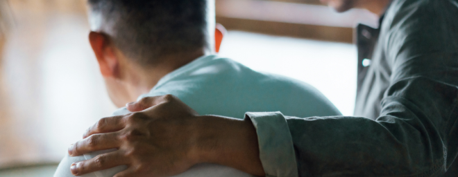 Male caregiver wrapping arm around son