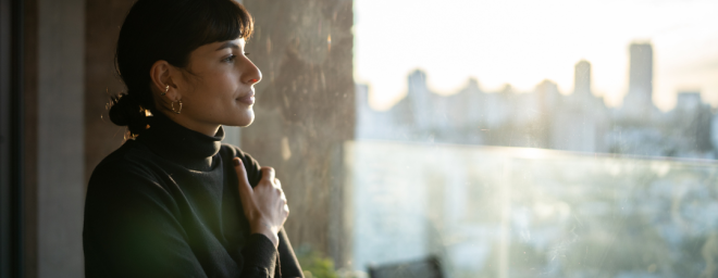 A woman looking out of an office window, deep in thought