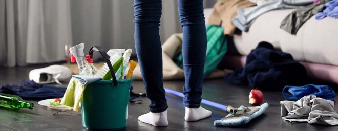 Picture of someone's legs standing in a room with their cleaning supplies, ready to start cleaning.