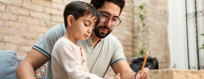 Picture of a father sitting down with his child to write goals down.