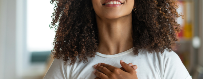 A person smiling with both hands on their chest.