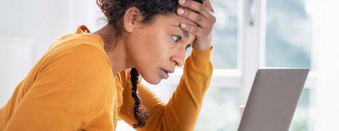 Picture of someone sitting down, seemingly stressed, with her palm on her forehead.