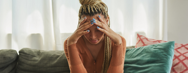 Photo of a sad young adult female, holding her head in her hands