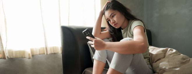 Picture of a woman scrolling through her phone with a worried look on her face 