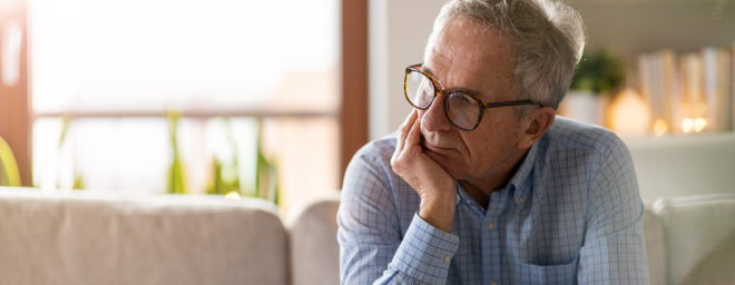 Picture of a man sitting on a couch with a worried look on his face.