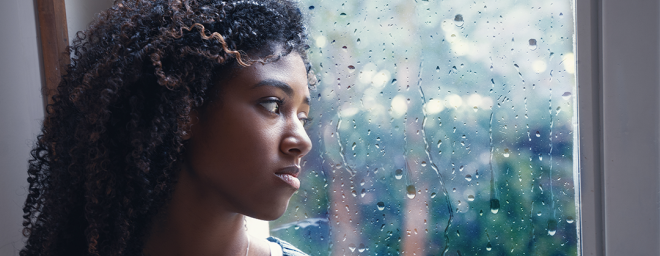 A women staring out the window watching the rain