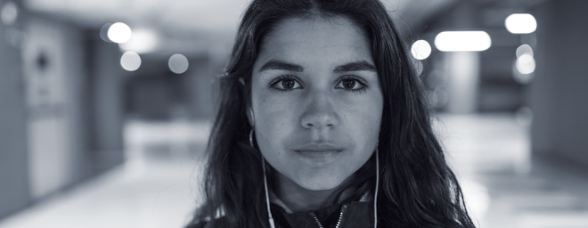 Teenage girl wearing headphones, looking at the camera with a pensive look