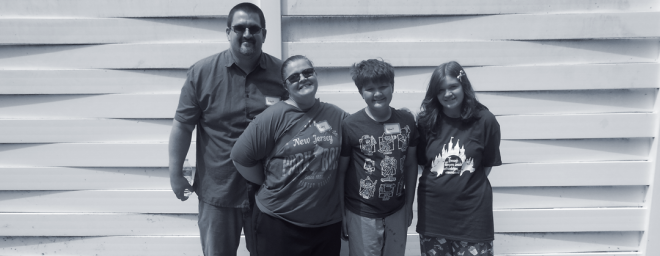 Kayleigh's family photo - a photo featuring dad, mom and brother alongside Kayleigh standing in front of a white fence. 