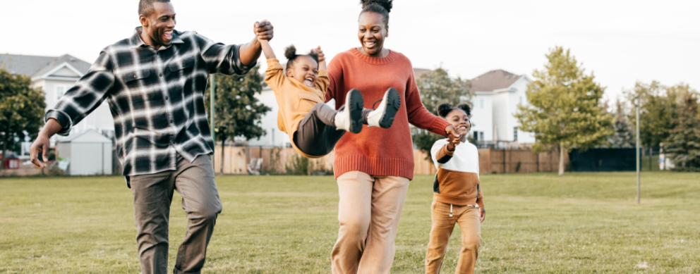 Black family playing together in an open field