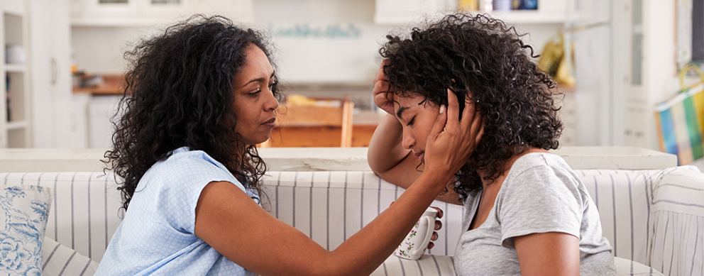 A Black mother comforting her teen daughter who is distressed