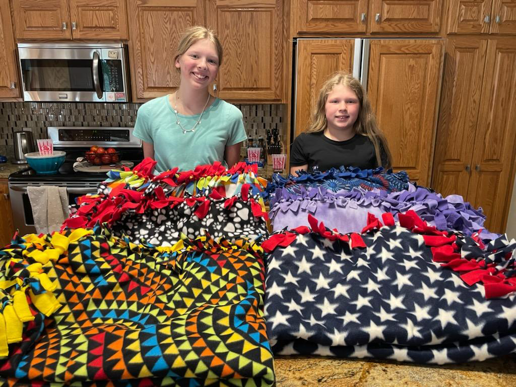 Sharon's grandkids showcasing off the tie blankets they made for Nexus Family Healing youth