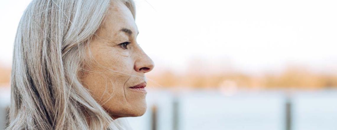 Older woman looking out onto a lake pensively