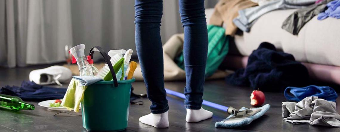 Picture of someone's legs standing in a room with their cleaning supplies, ready to start cleaning.