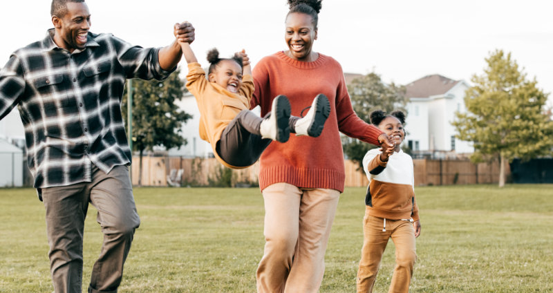 Black family playing together in an open field
