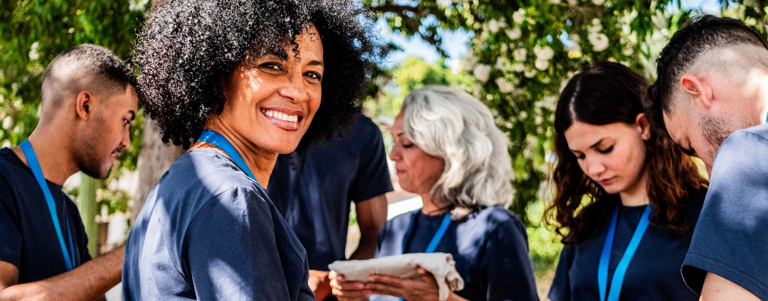 group of adults working together with a multiracial female smiling at the camera