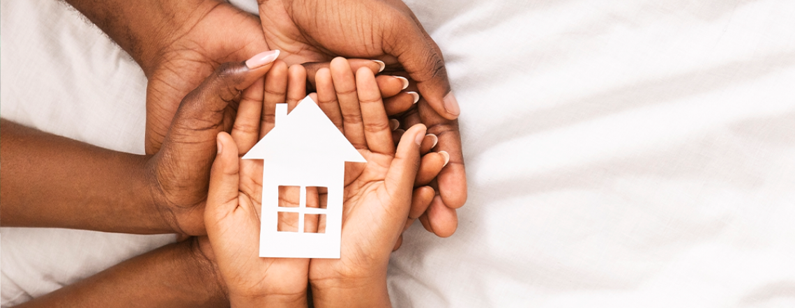 Parents and children's hands holding a house