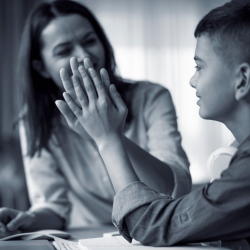 woman giving a student a high five while he completes his studies.