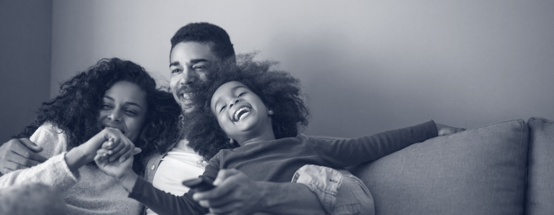 Two adults and child laughing on couch